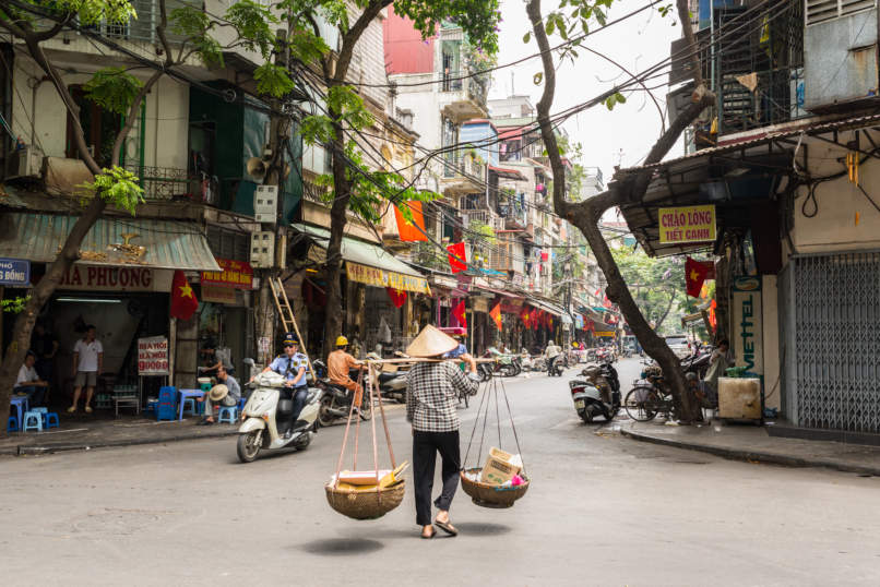 Street vendor transporting goods in baskets in Hanoi